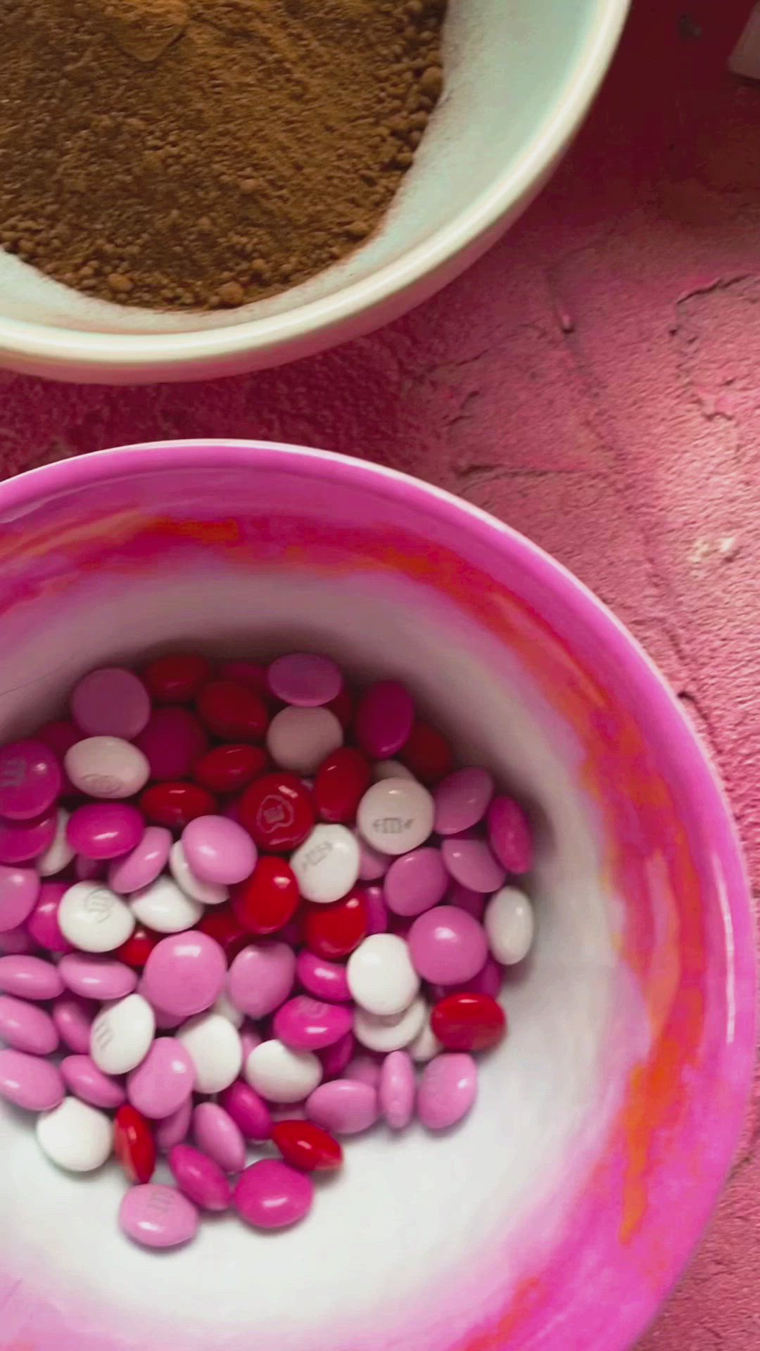 This may contain: three chocolate covered desserts sitting on top of a pink table