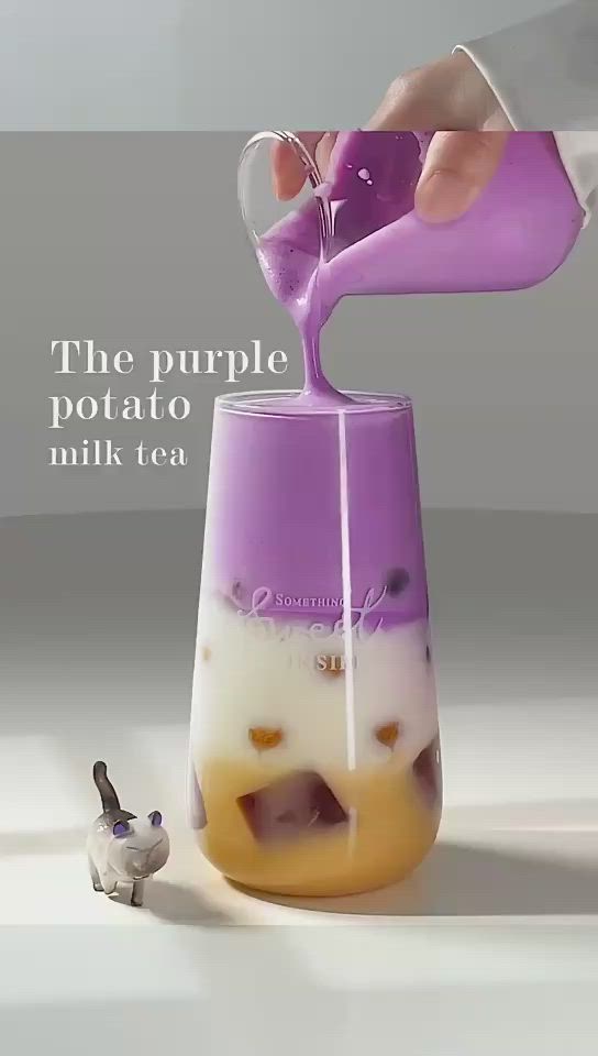 This may contain: a person pours liquid into a purple and white drink in a small glass cup