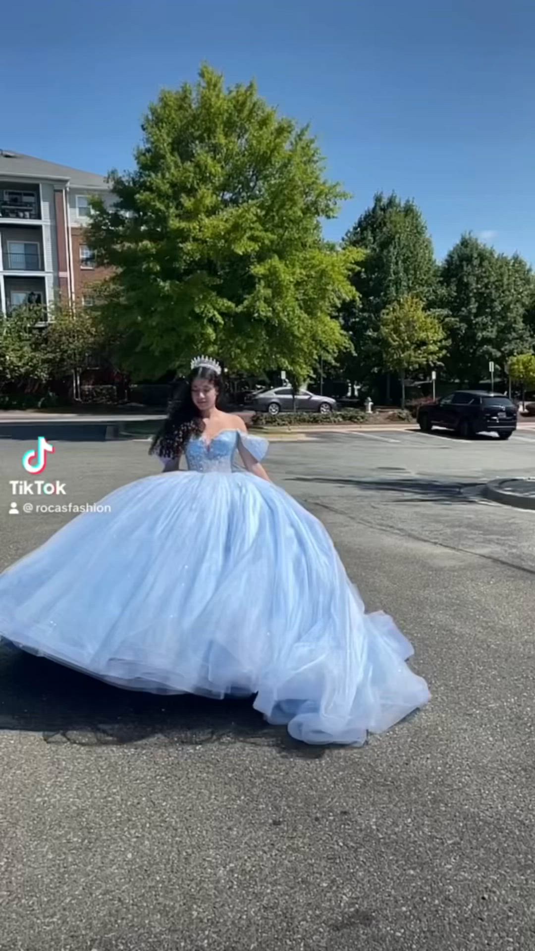 This may contain: a woman in a blue ball gown is standing on the street with her back to the camera