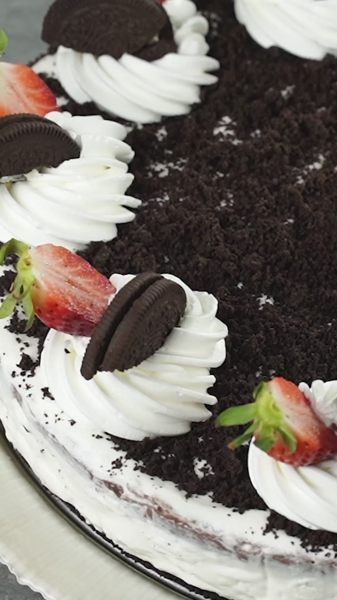 This may contain: a cake with white frosting, chocolate cookies and strawberries on top