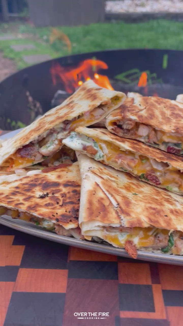 This may contain: several quesadillas stacked on top of each other in front of an open fire pit