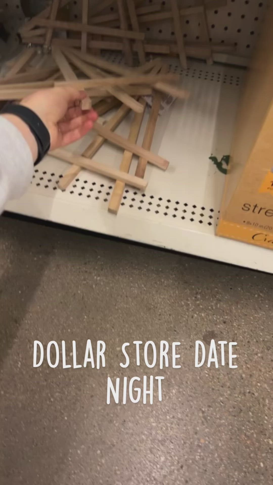 This may contain: a person reaching for some sticks on the floor with text reading dollar store date night