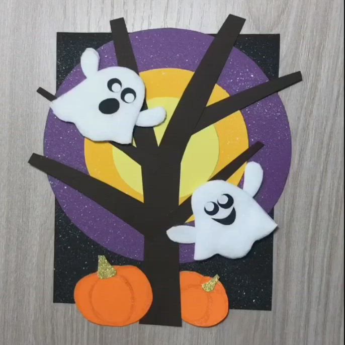 This may contain: a paper plate with ghost and pumpkins on it, sitting next to a tree