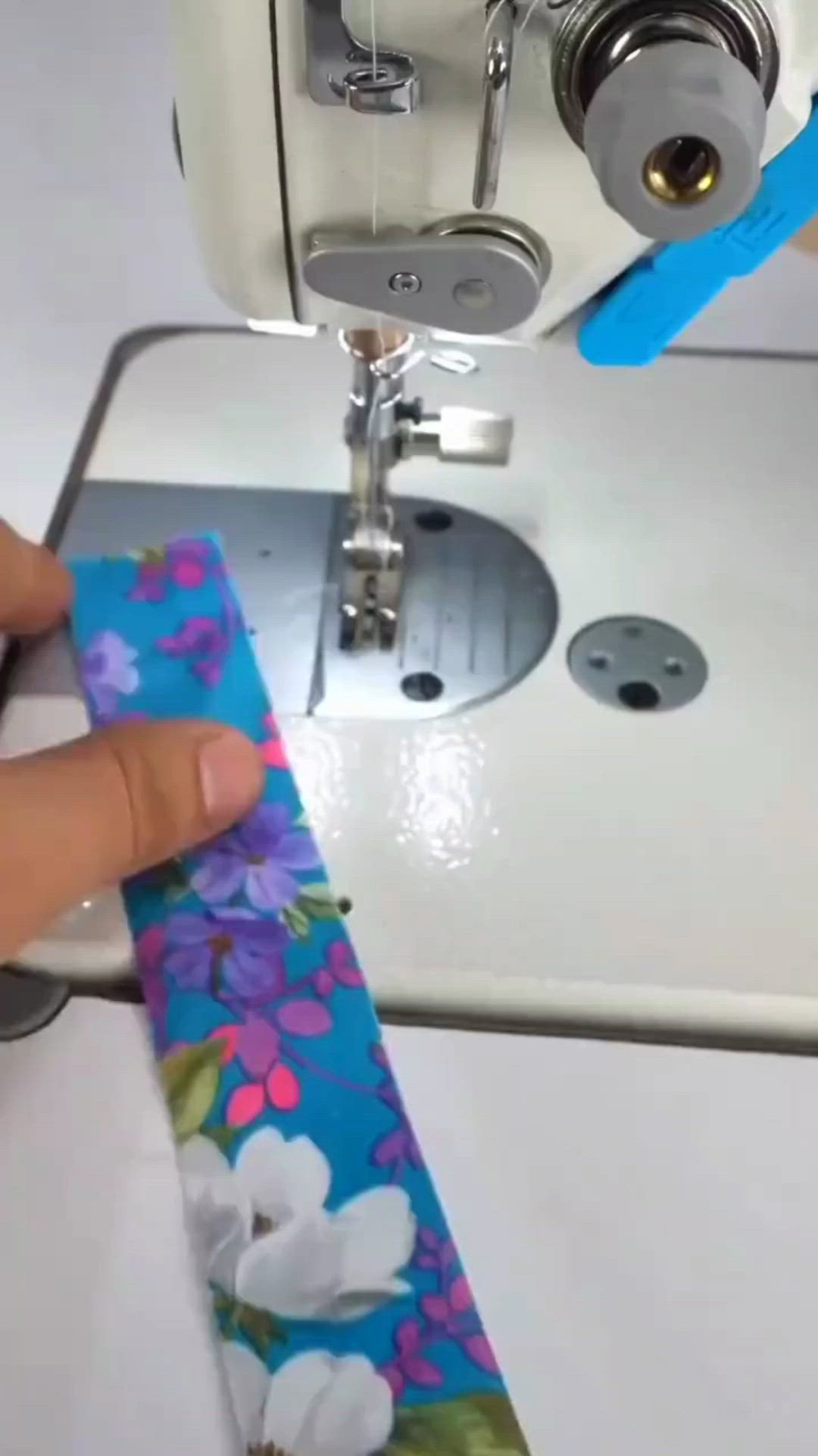 This may contain: someone is using a sewing machine to sew on a flowered fabric with scissors