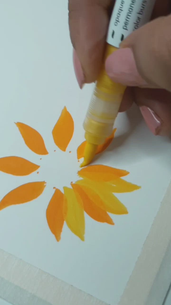 This may contain: someone is painting an orange flower on a piece of white paper with yellow and red paint