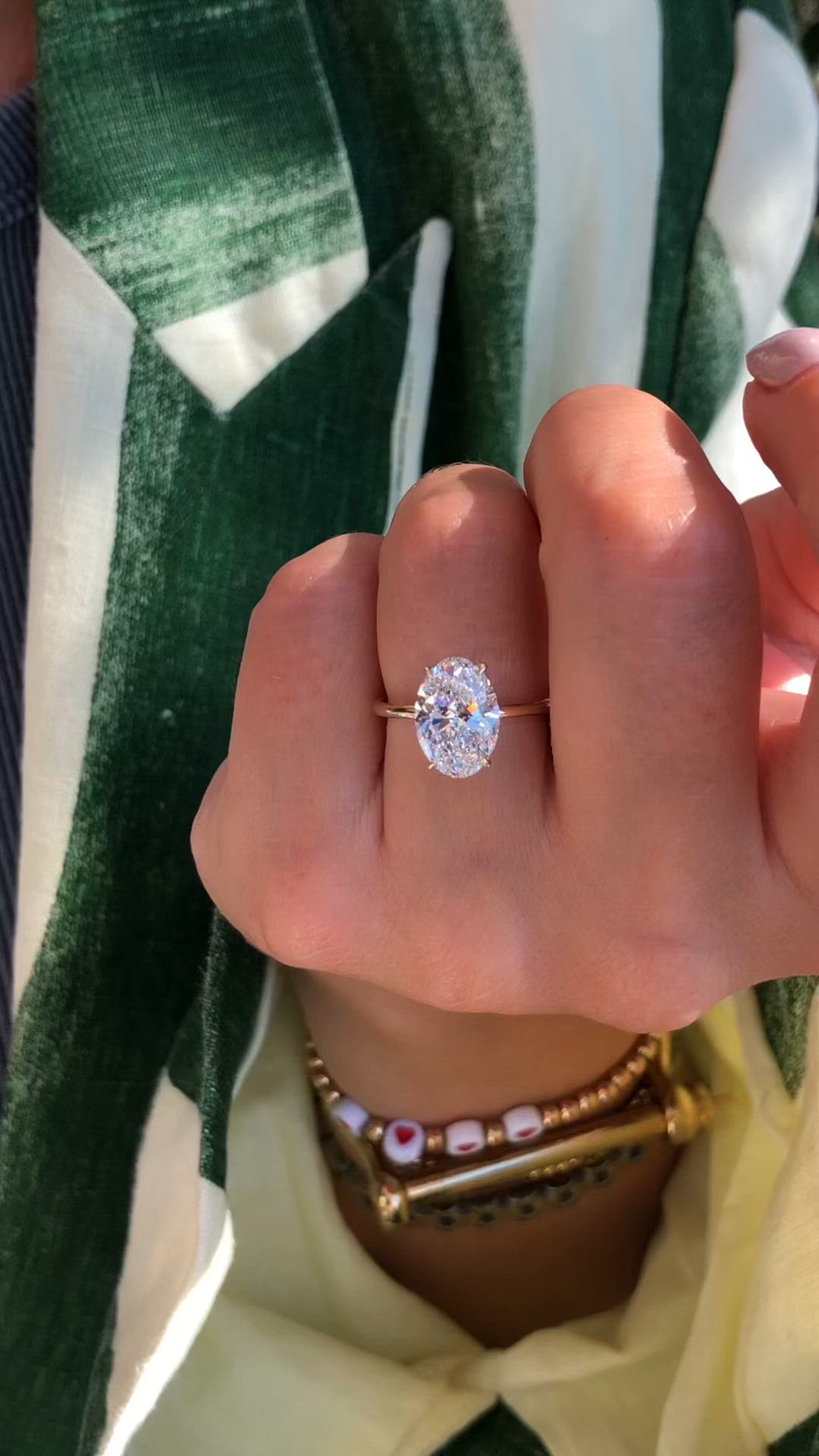 This may contain: a woman's hand with a diamond ring on top of her finger, showing the center stone