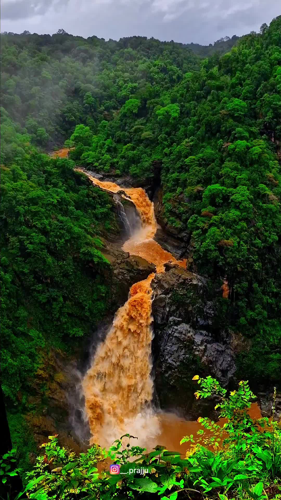 This may contain: a large waterfall surrounded by lush green trees