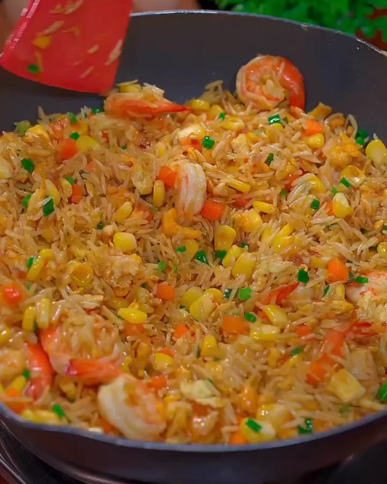 This may contain: a pan filled with rice and shrimp on top of a stove