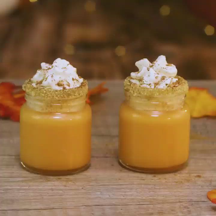 This may contain: two pumpkin pie shots sitting on top of a wooden table