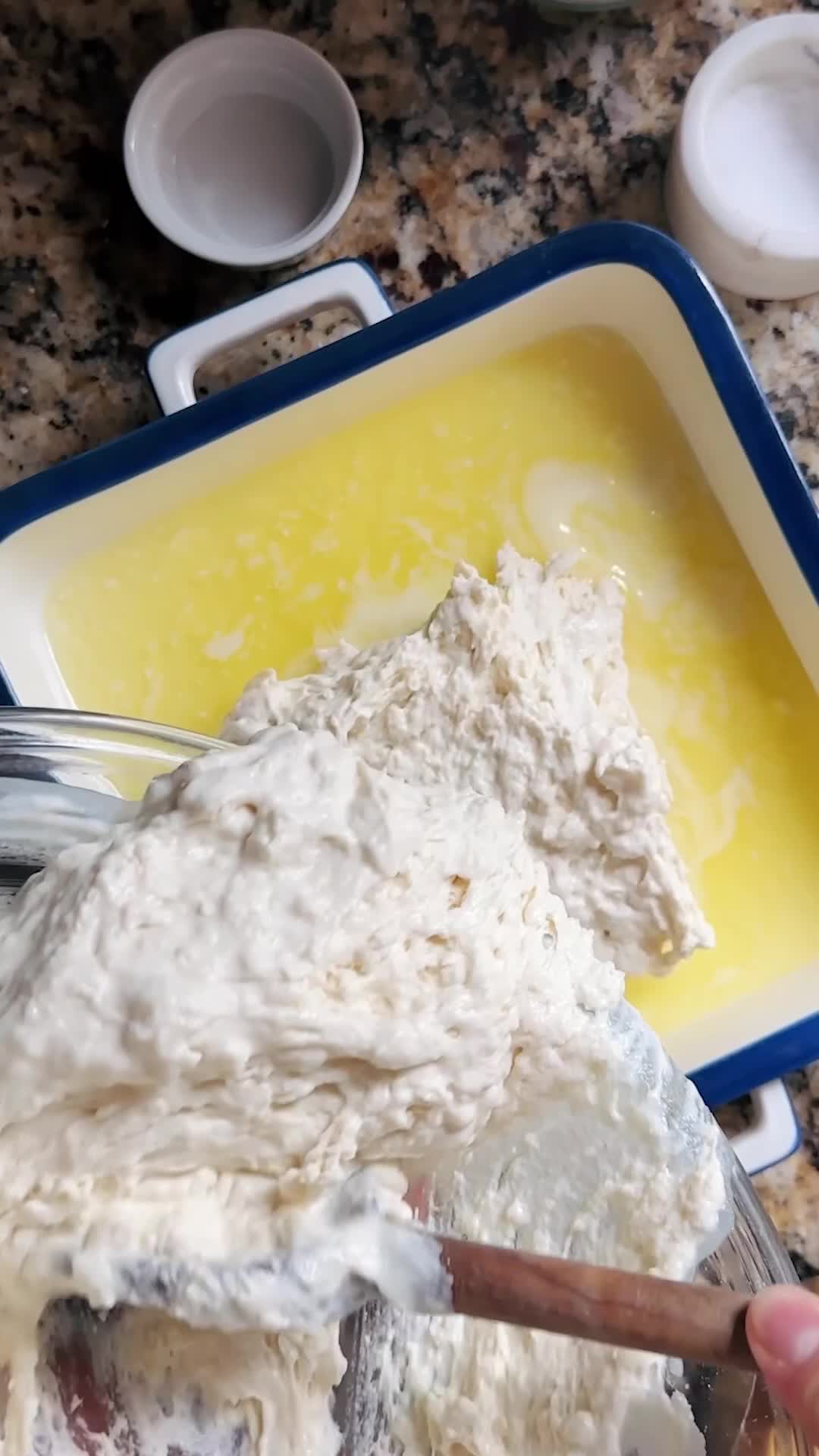 This may contain: a person holding a spoon in front of a casserole dish with bread and honey