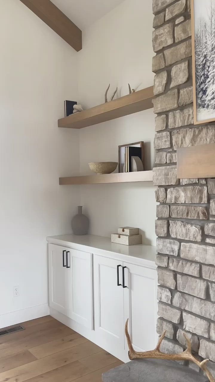 This may contain: a stone fireplace with shelves and books on the top shelf, along with a deer antler's head