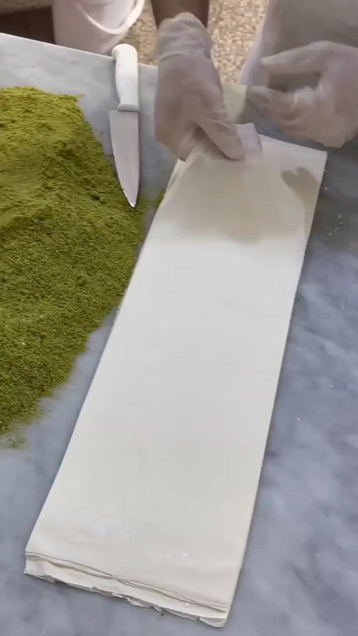 This may contain: a person cutting up some green stuff on top of a white table cloth with a knife