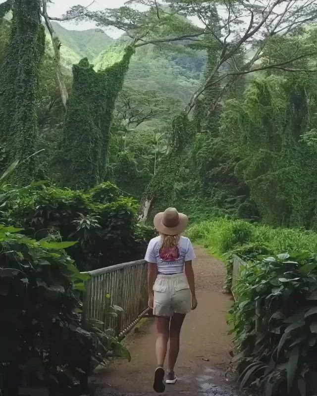 This may contain: a woman walking down a path in the jungle