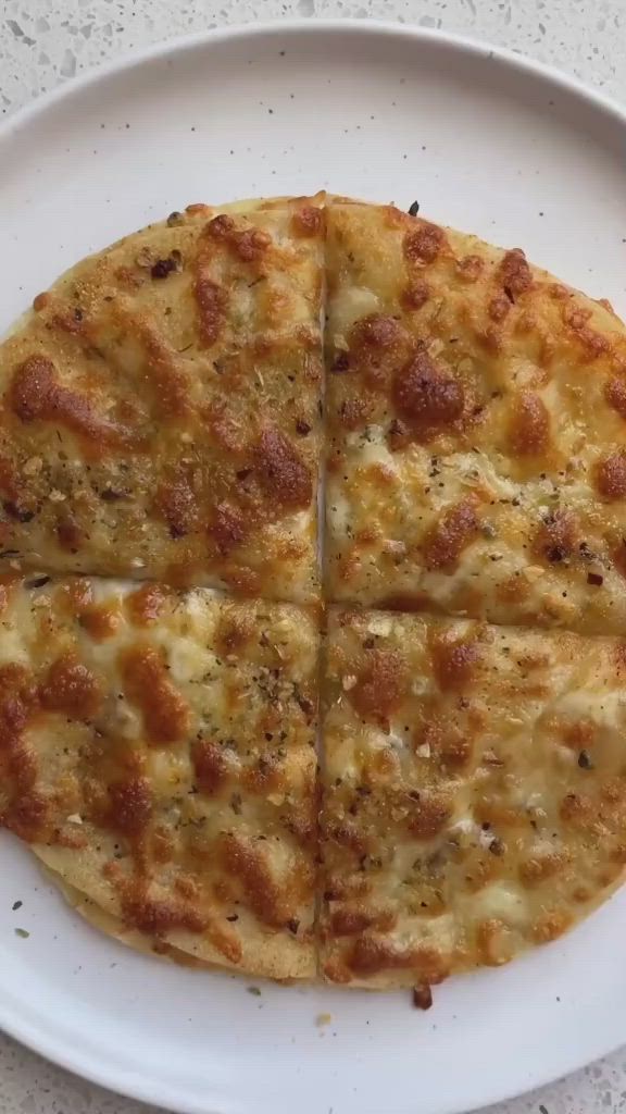 This may contain: a white plate topped with a cheese pizza cut into four slices on top of it