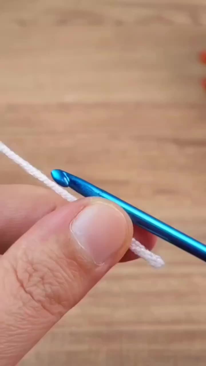 This may contain: a person holding a blue and white crochet hook in their left hand while knitting