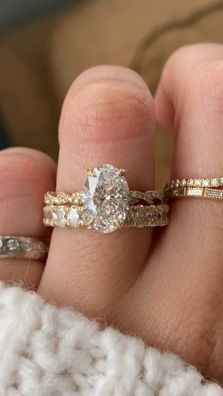 This may contain: a woman's hand with two wedding rings on top of her finger and the ring has a pear shaped diamond in it