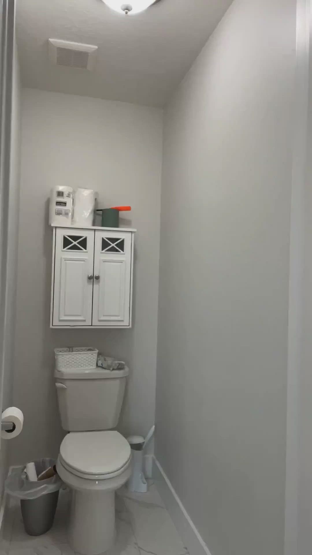 This may contain: a white toilet sitting in a bathroom next to a shelf