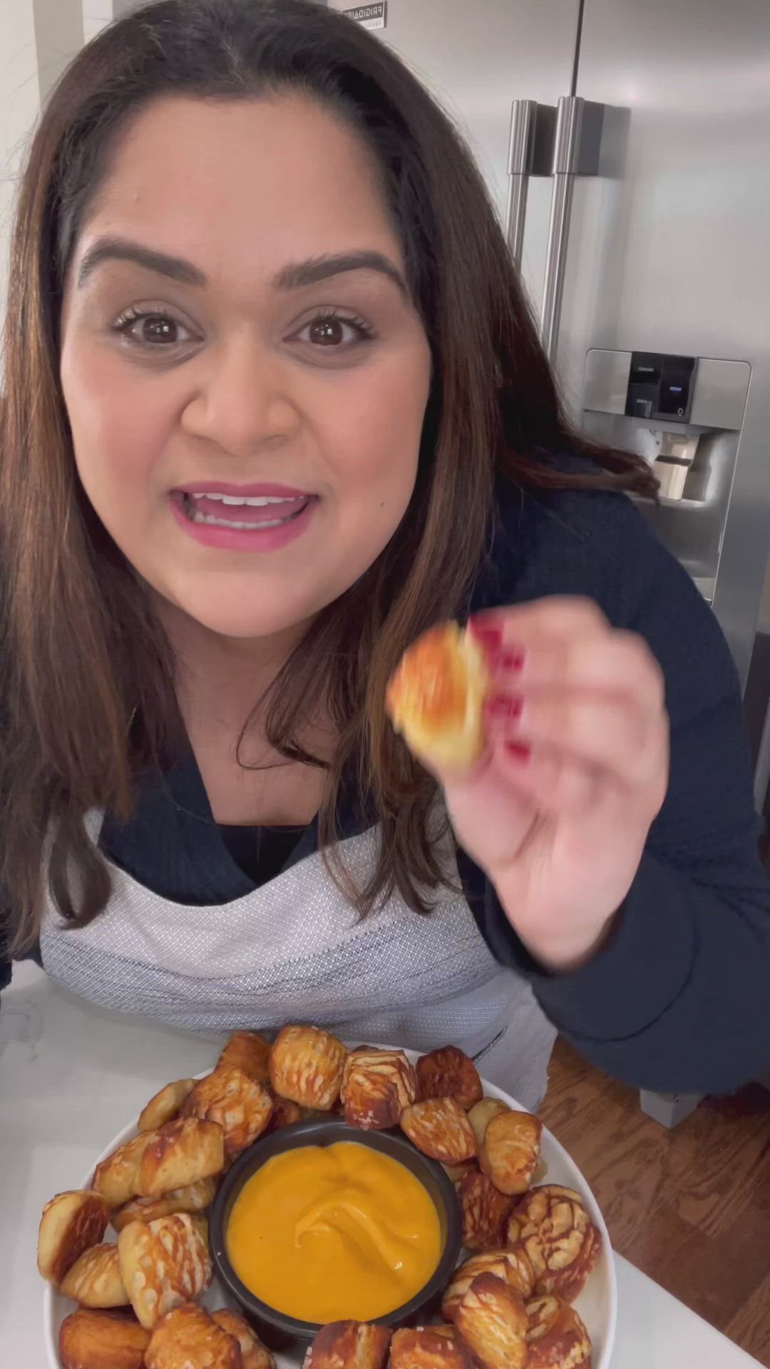 This may contain: a woman is holding up a doughnut and dipping sauce