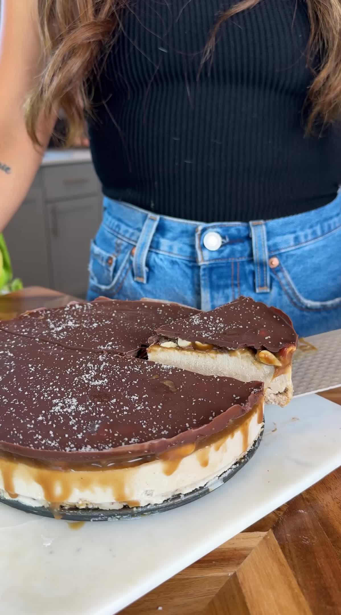 This may contain: a woman is cutting into a chocolate and white cake on a table with other desserts