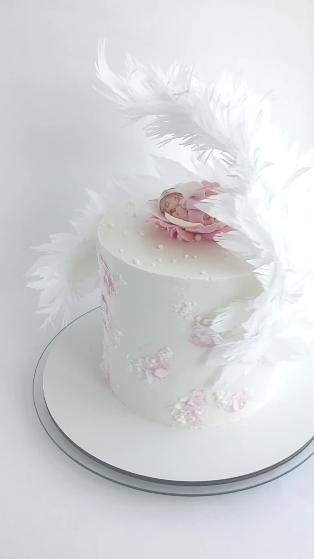 This may contain: a small white cake with feathers on top