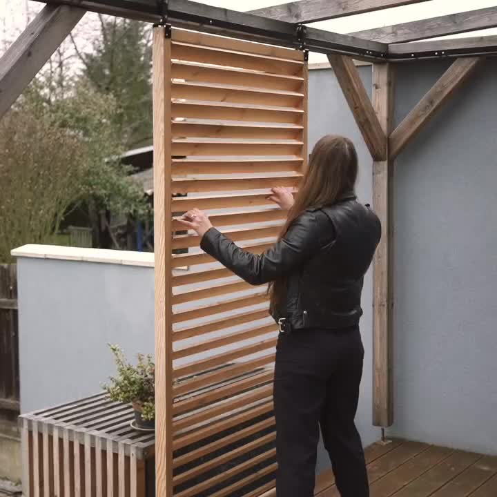 This may contain: a woman standing next to a wooden slatted door on top of a roof