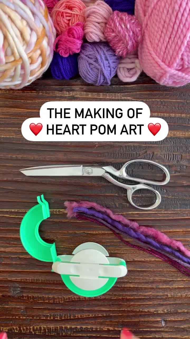 This may contain: the making of heart pom art with yarn and scissors