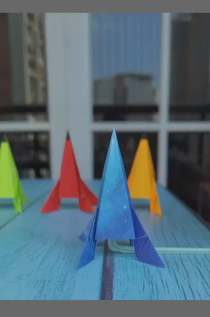 This may contain: colorful paper airplanes sitting on top of a wooden table