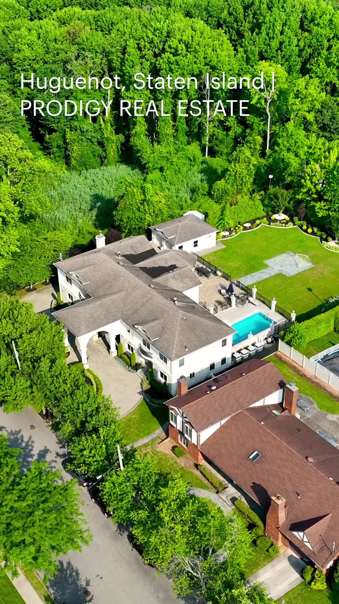 This may contain: an aerial view of a large home surrounded by lush green trees and greenery, with the words hyggenio state island prodigy real estate