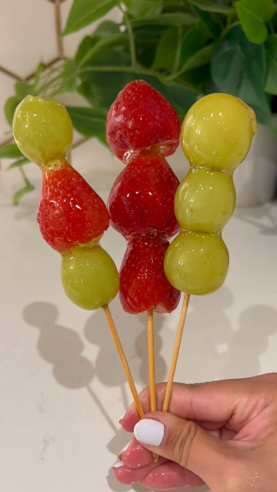 This may contain: a person is holding some fruit on a stick with gummy bears and strawberries