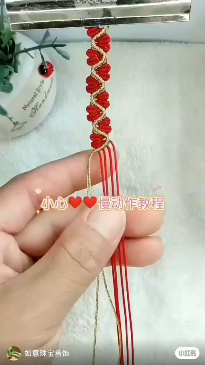 This may contain: a person holding a red string with hearts on it