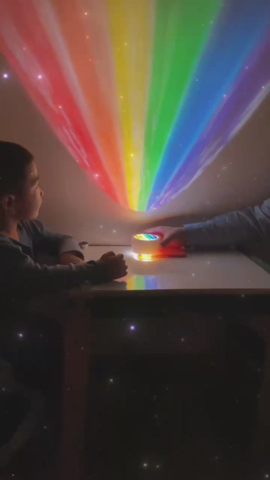 This may contain: two children sitting at a table with a rainbow light in the background