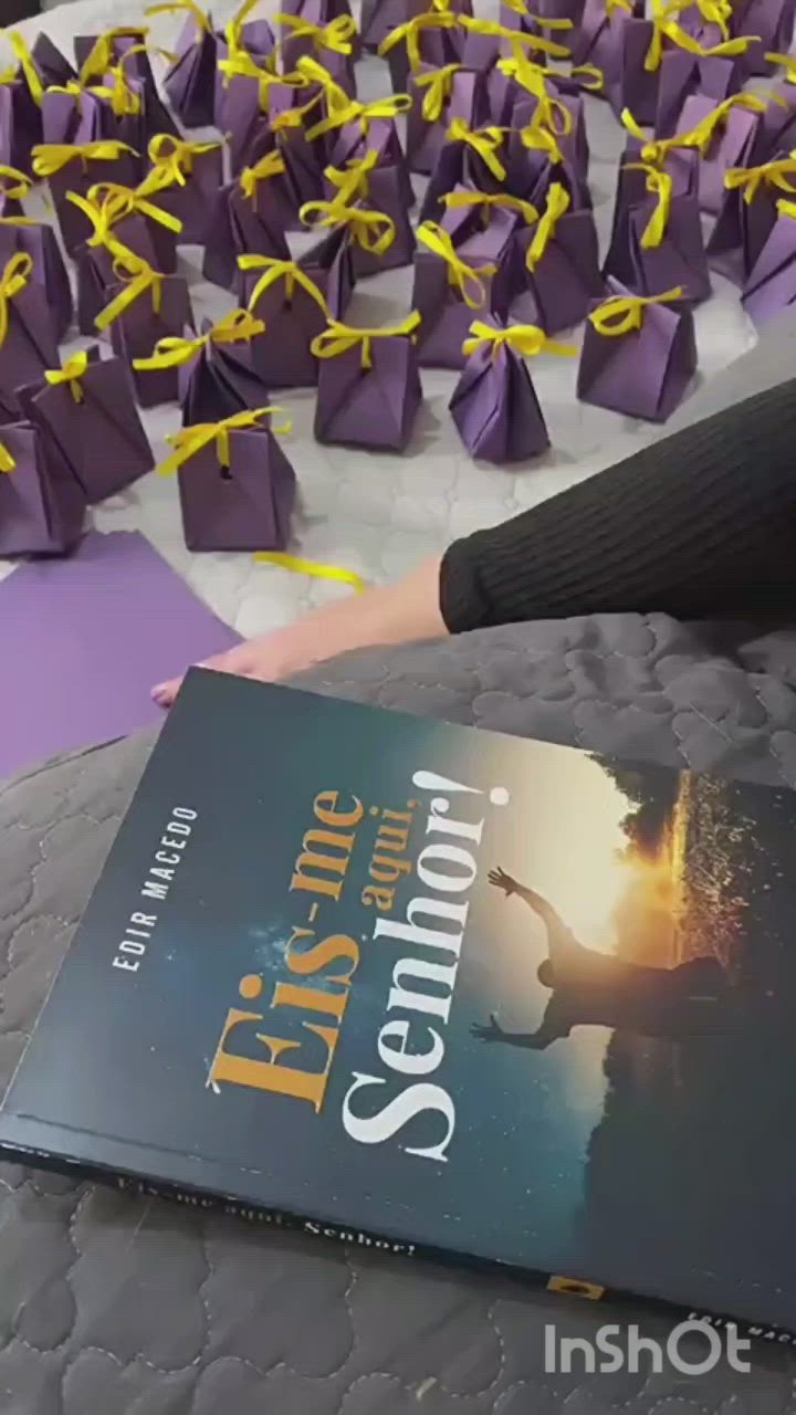 This may contain: a person is holding a book in front of purple origami pieces on a bed