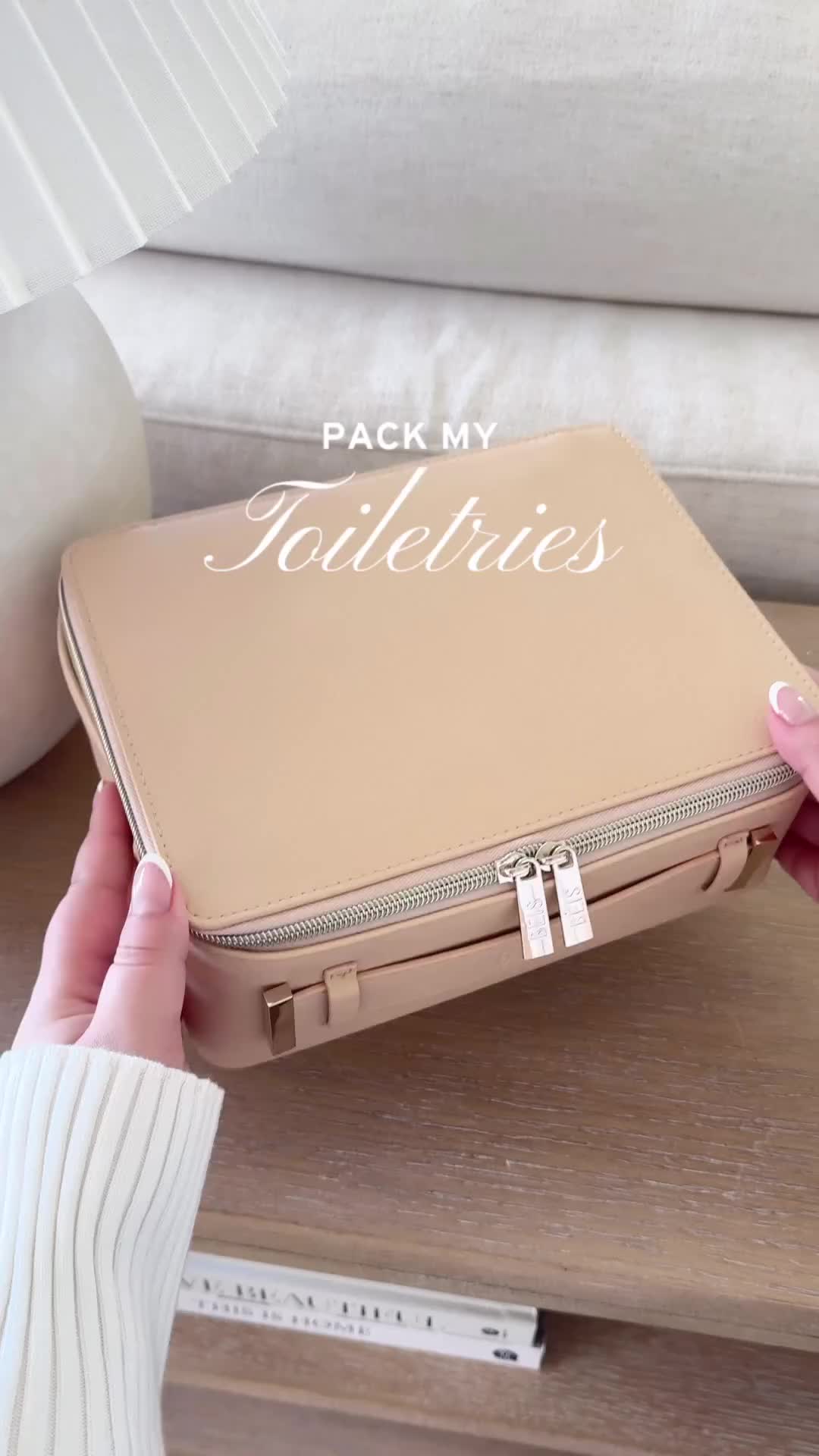 This may contain: a person holding a tan suitcase with the words pack my toiletries on it