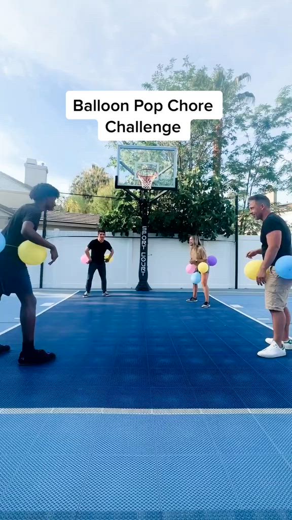 This may contain: two men are playing basketball on an outdoor court with balloons in the shape of people