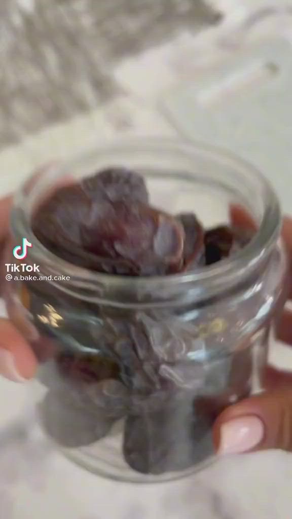 This may contain: a person holding a glass jar filled with raisins