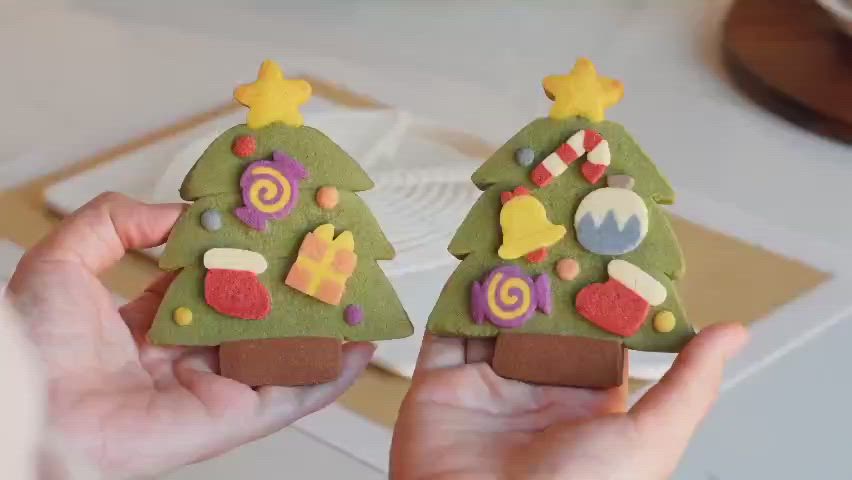 This may contain: two decorated cookies in the shape of christmas trees are being held by someone's hands