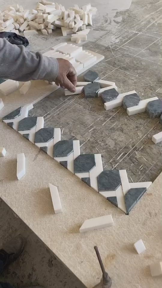 This may contain: a man working on some kind of art project with white and black tiles in the shape of hexagons