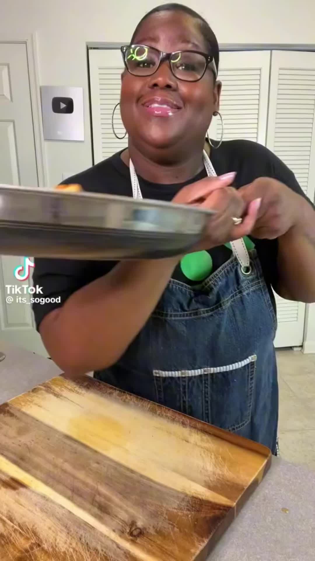 This may contain: a woman in glasses is cutting wood with a large knife on top of a table