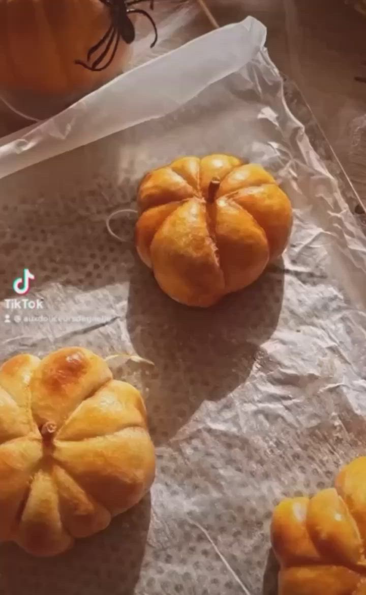 This may contain: three pumpkin shaped pastries sitting on top of a piece of paper