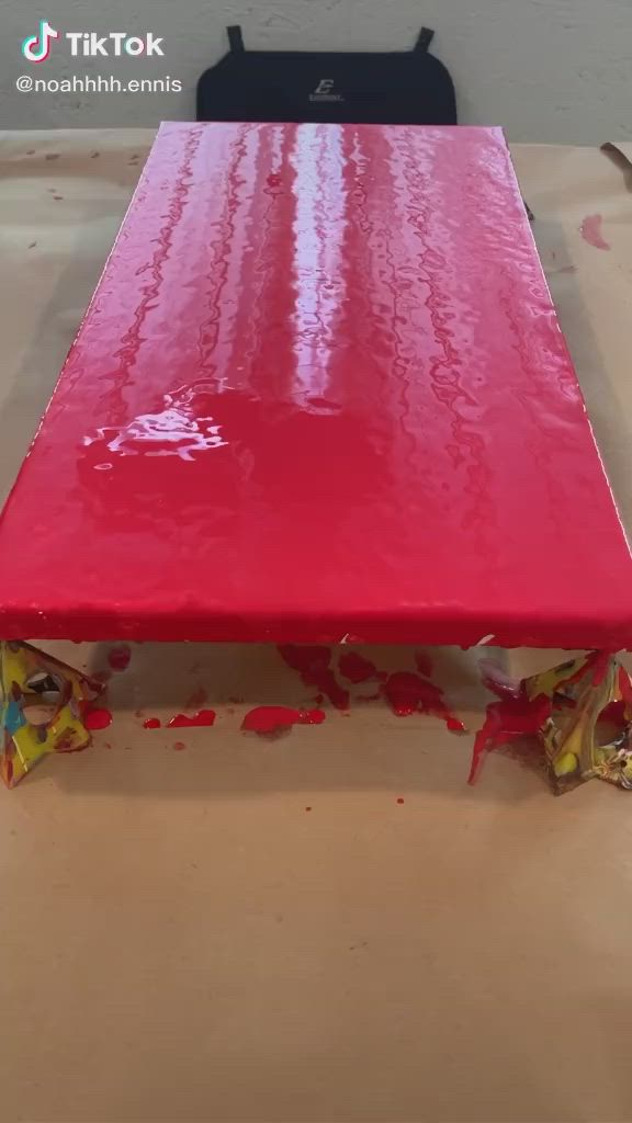 This may contain: someone is decorating a cake with white and black icing on red trays