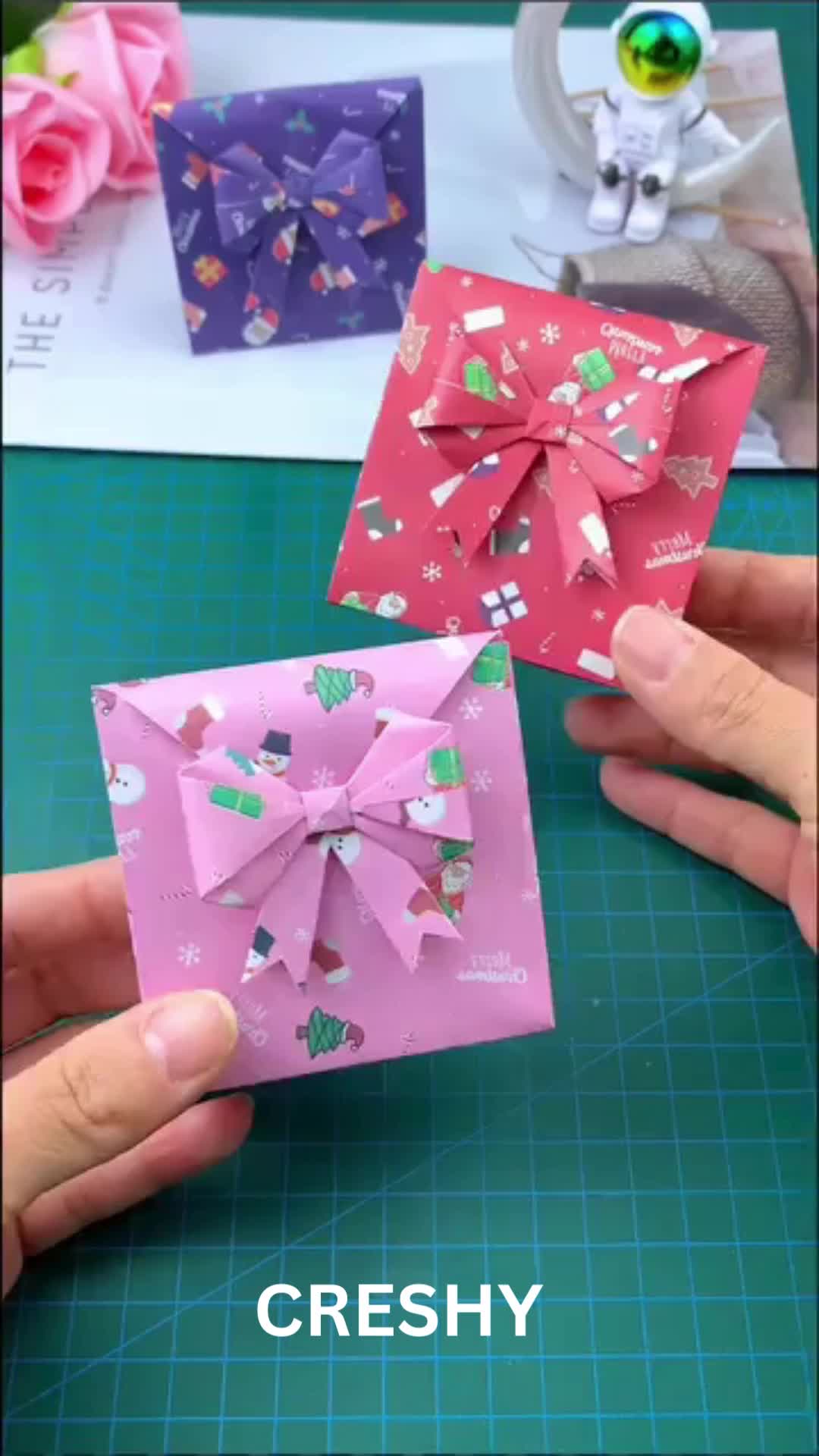 This may contain: two hands are holding origami pieces with bows