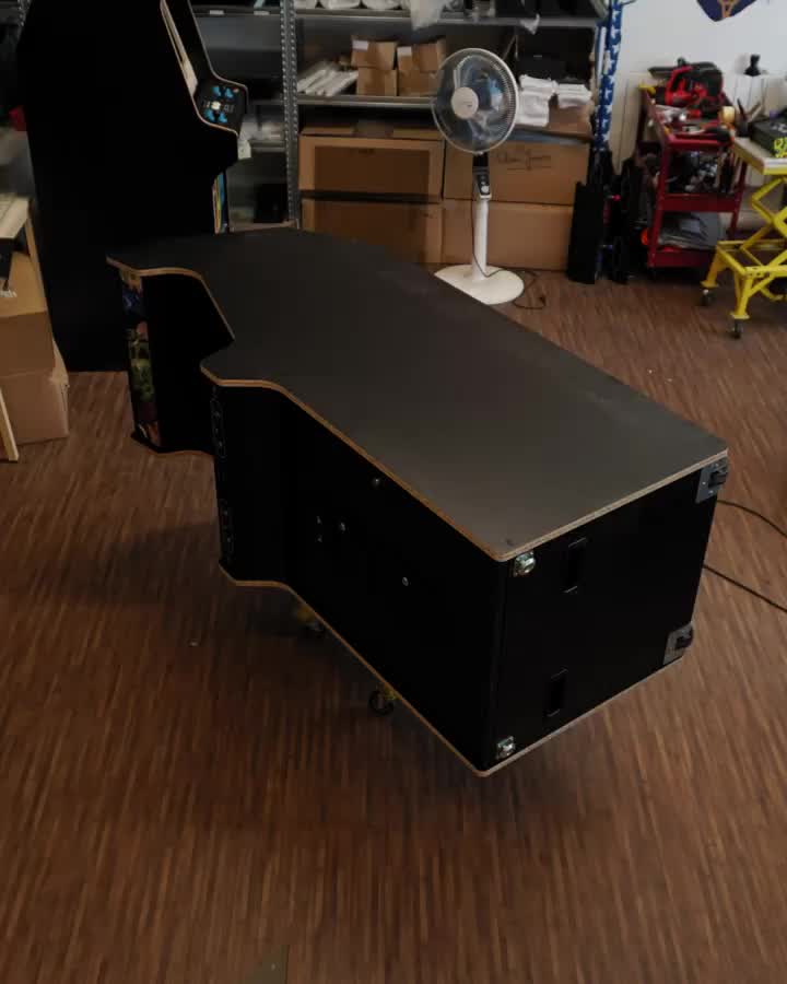 This may contain: a black desk sitting on top of a hard wood floor next to a wall mounted fan