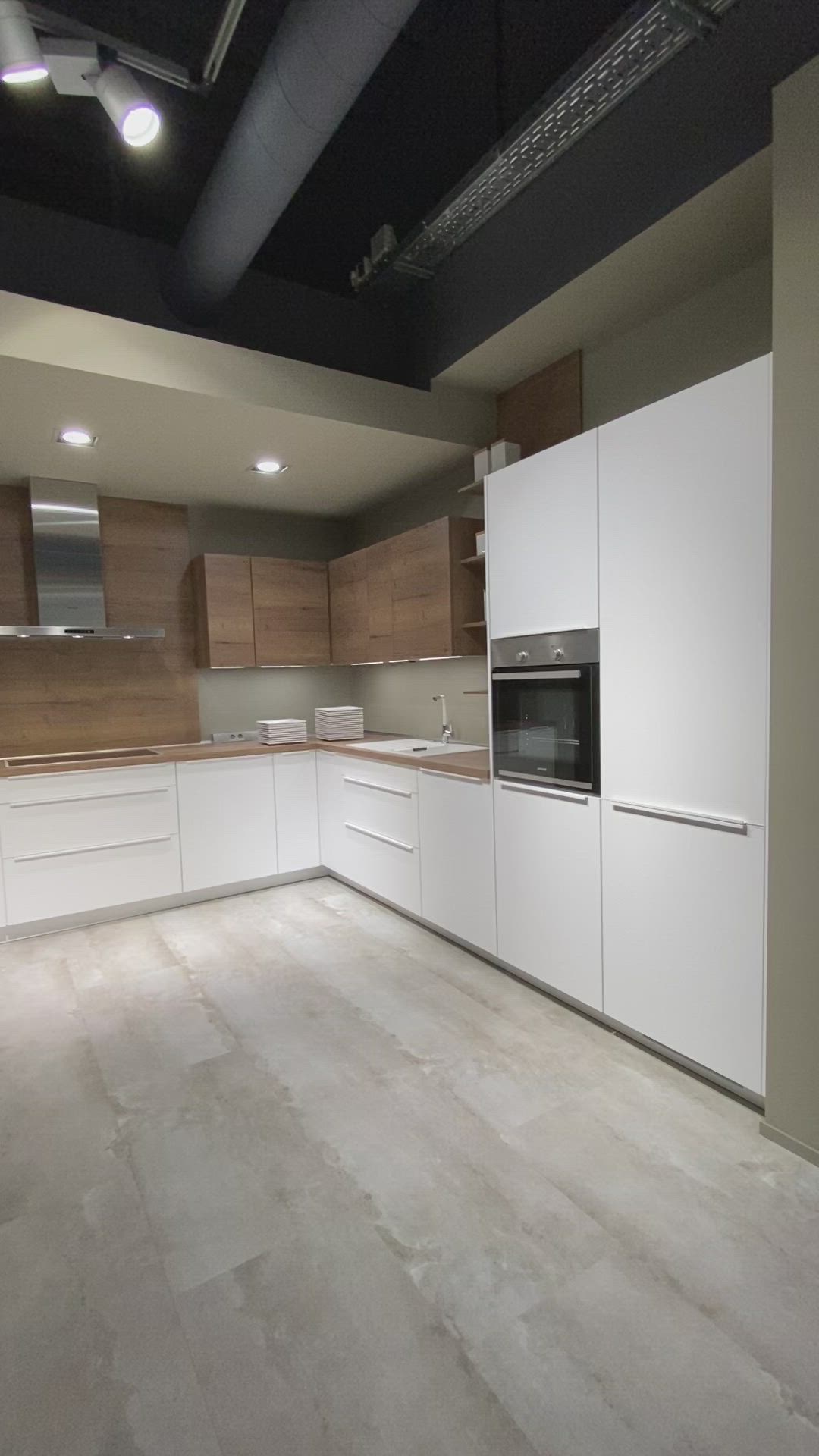 This may contain: an empty kitchen with white cabinets and wood flooring is seen in this image from the inside