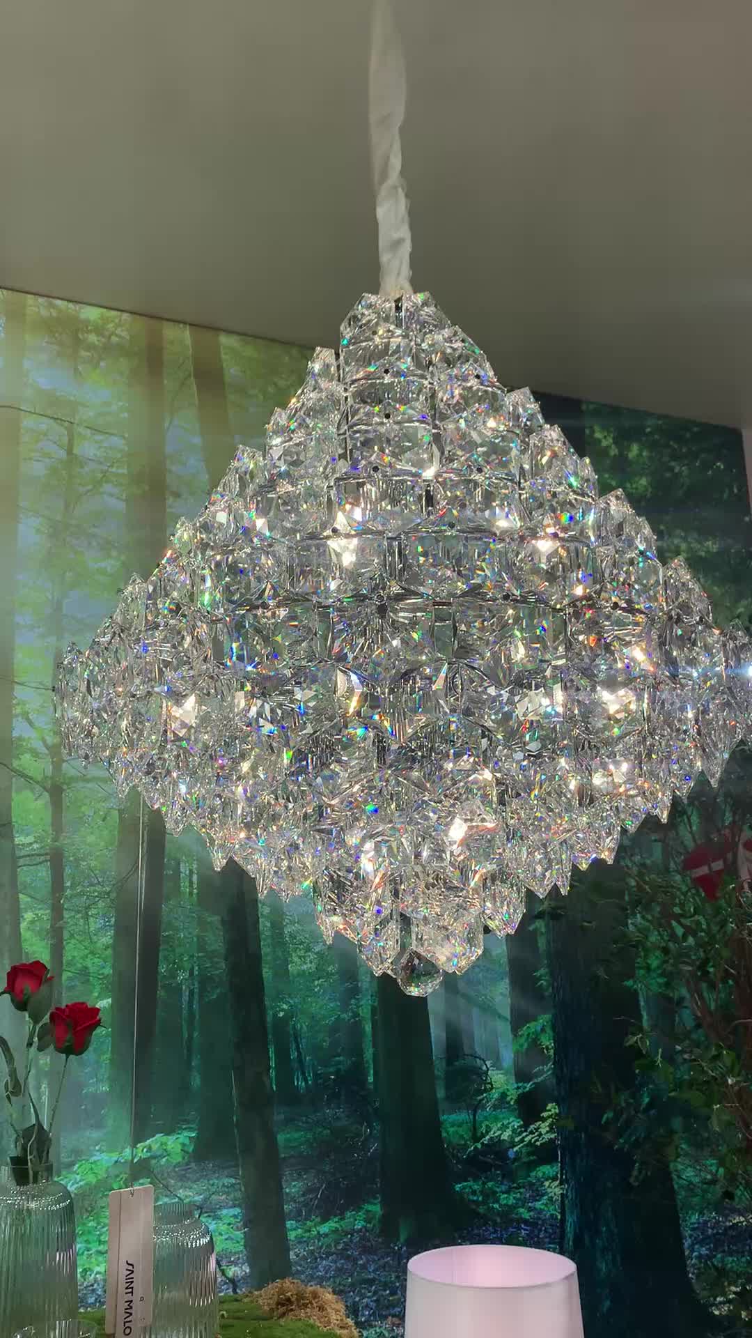 This may contain: a crystal chandelier hanging from the ceiling in a room with flowers and vases