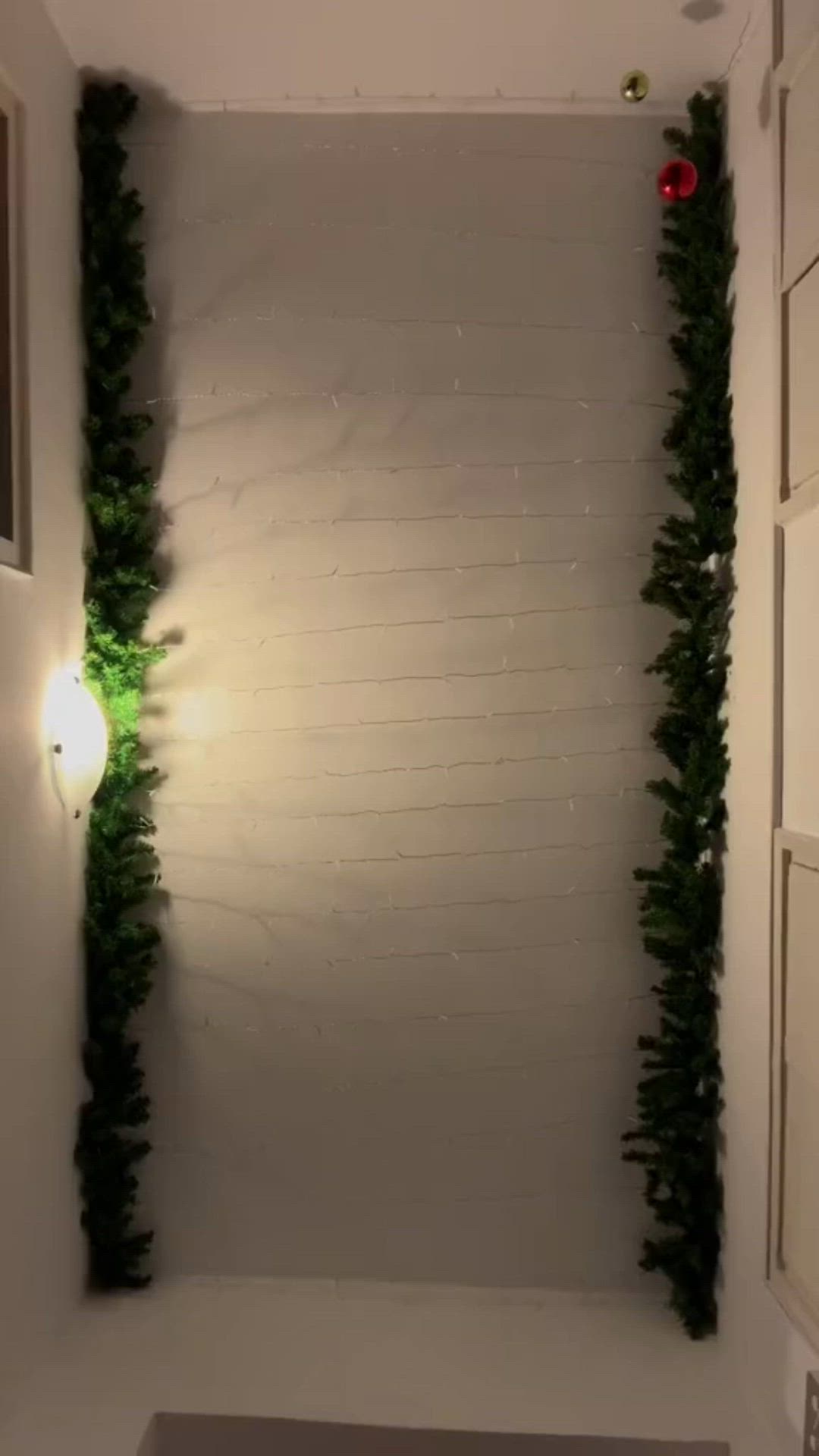 This may contain: christmas decorations hanging from the ceiling in a room with white walls and green trimmings