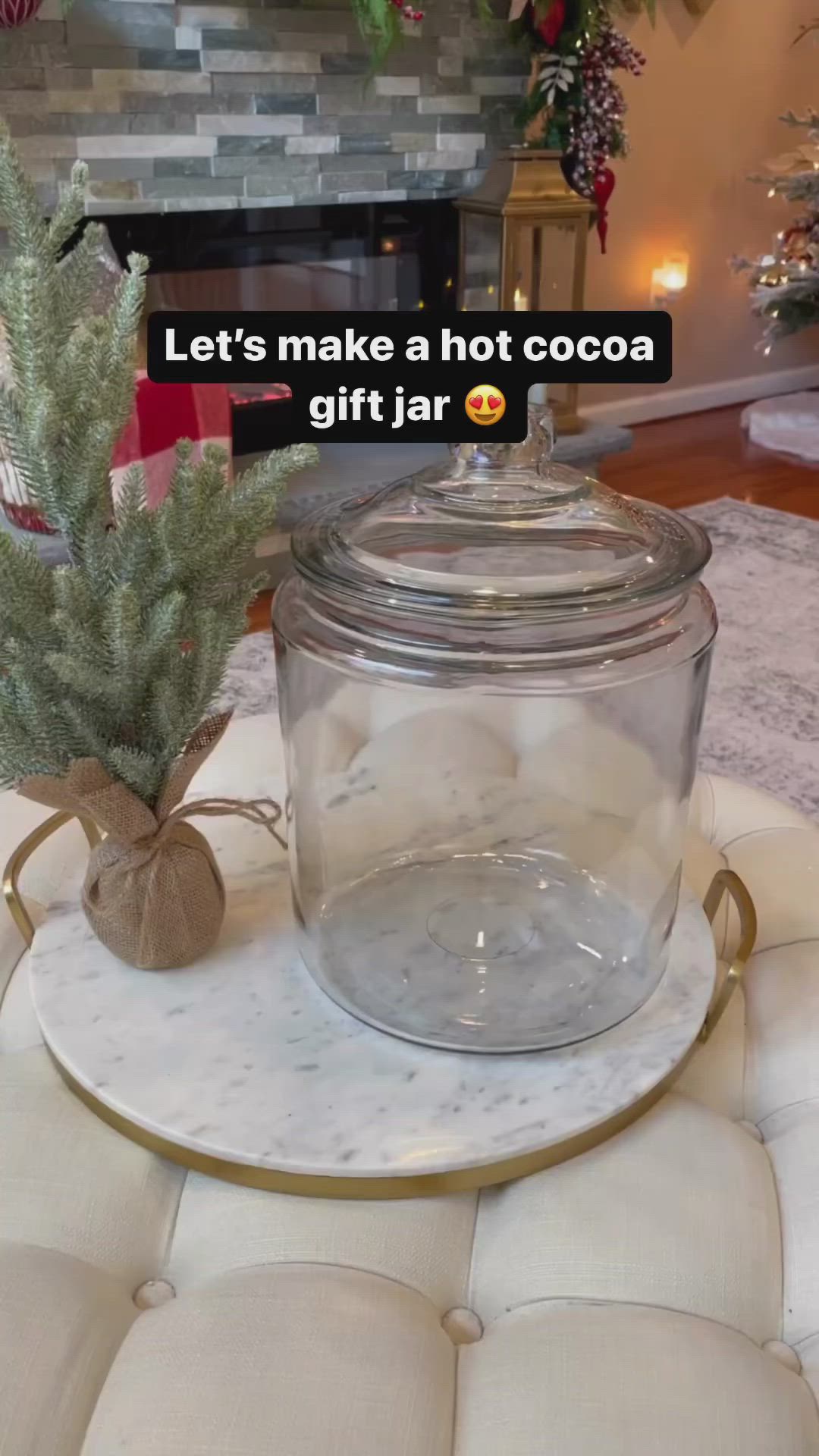 This may contain: a glass jar filled with water sitting on top of a white plate next to a christmas tree