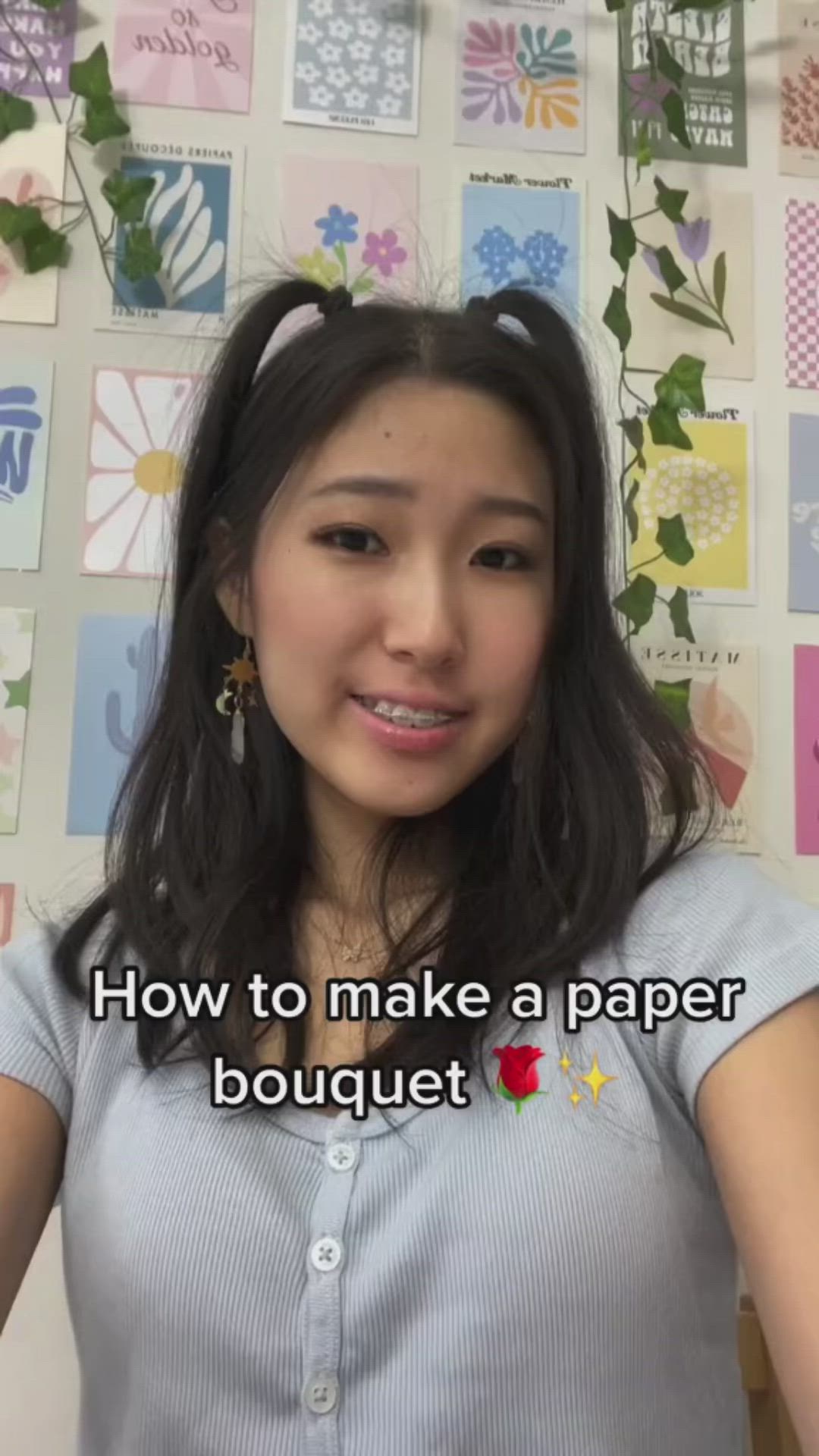 This may contain: a woman standing in front of a wall with flowers on it and the words how to make a paper bouquet