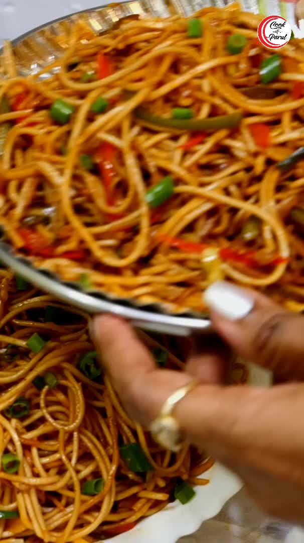 This may contain: a plate full of noodles and vegetables on a white table cloth with silverware in the background