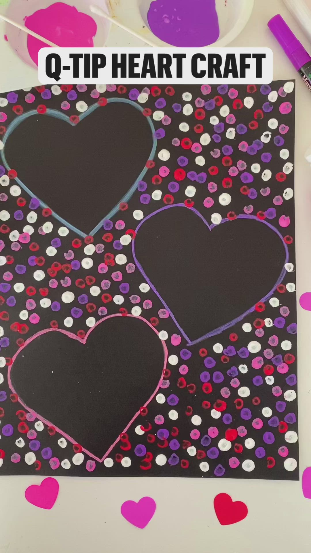 This may contain: two hearts on a black paper with pink and purple confetti in the background