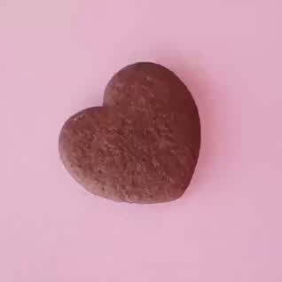 This may contain: a heart shaped rock sitting on top of a pink surface